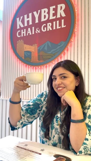 Mahnoor Raza holding a cup of chai at Khyber Chai & Grill